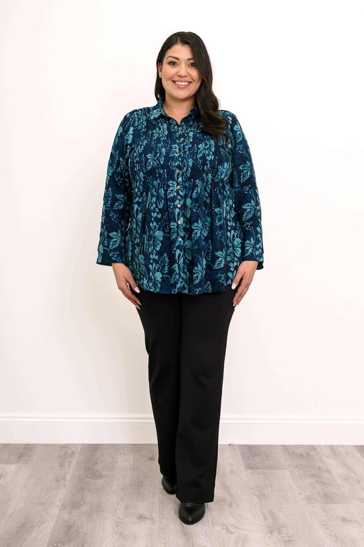 Woman modeling The Cindy blue floral smocked top and black pants, front view
