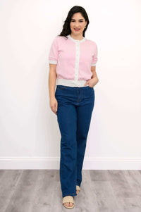 Full front view of model in pink two-tone sweater with faux pearl buttons and blue jeans