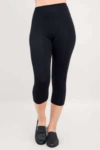 Front view of model wearing black high-waist capri leggings and black loafers