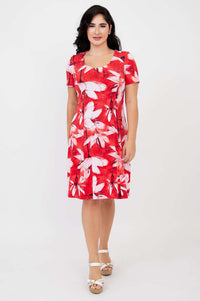 Woman in a red and white floral print dress, standing and facing forward with arms at sides.