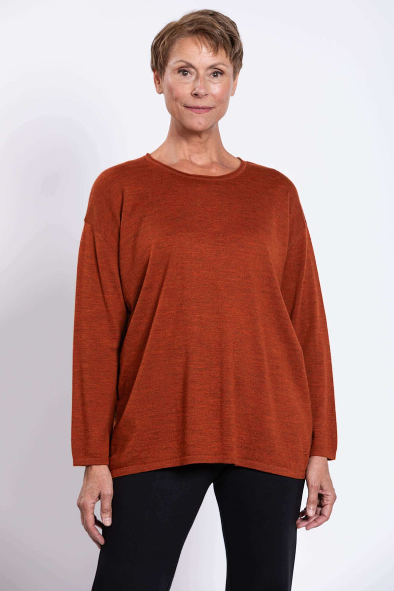 Front view of a woman wearing a rust-colored merino wool pullover sweater