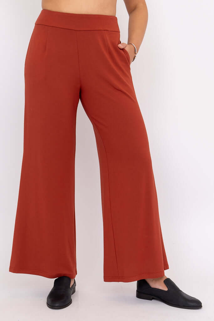 Front view of rust wide leg pants with pockets and black slip-on shoes
