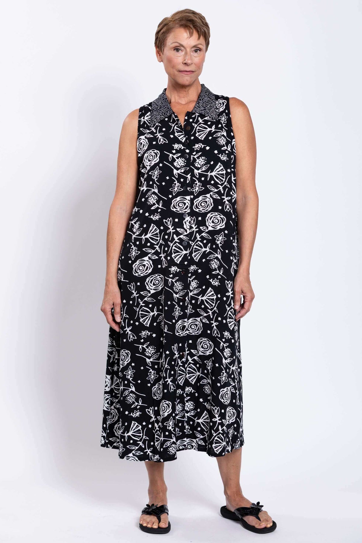 Front view of woman wearing a sleeveless black and white floral A-line dress