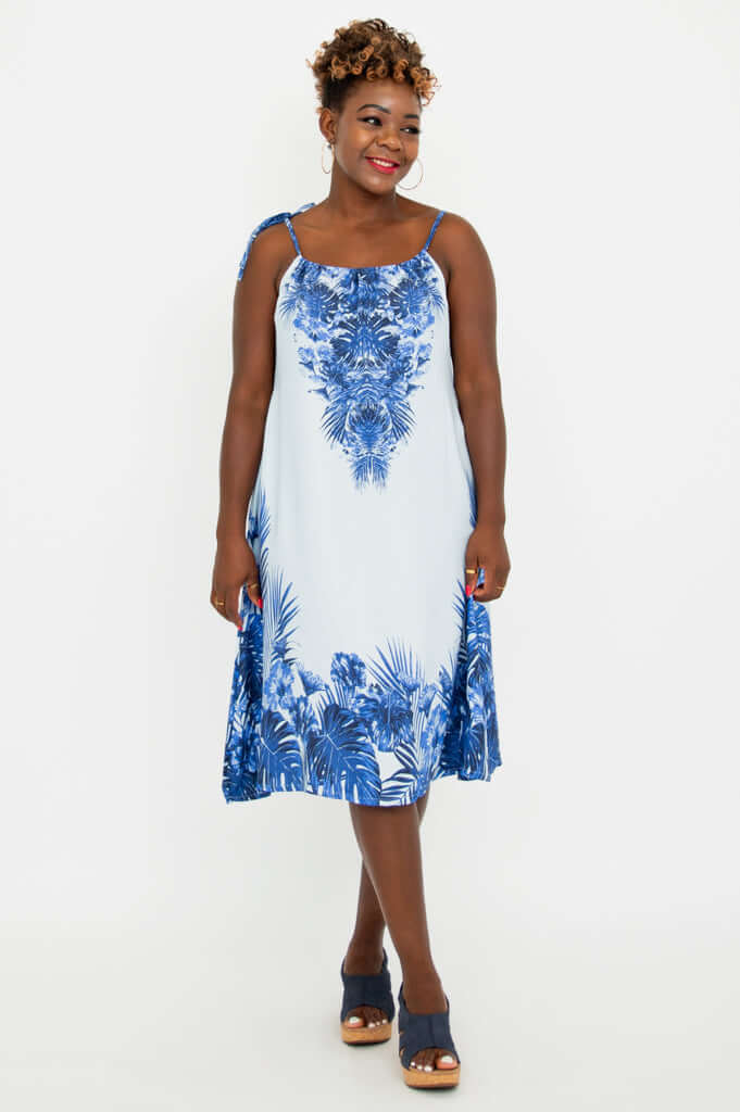 Woman wearing sleeveless blue palm print A-line dress, front view