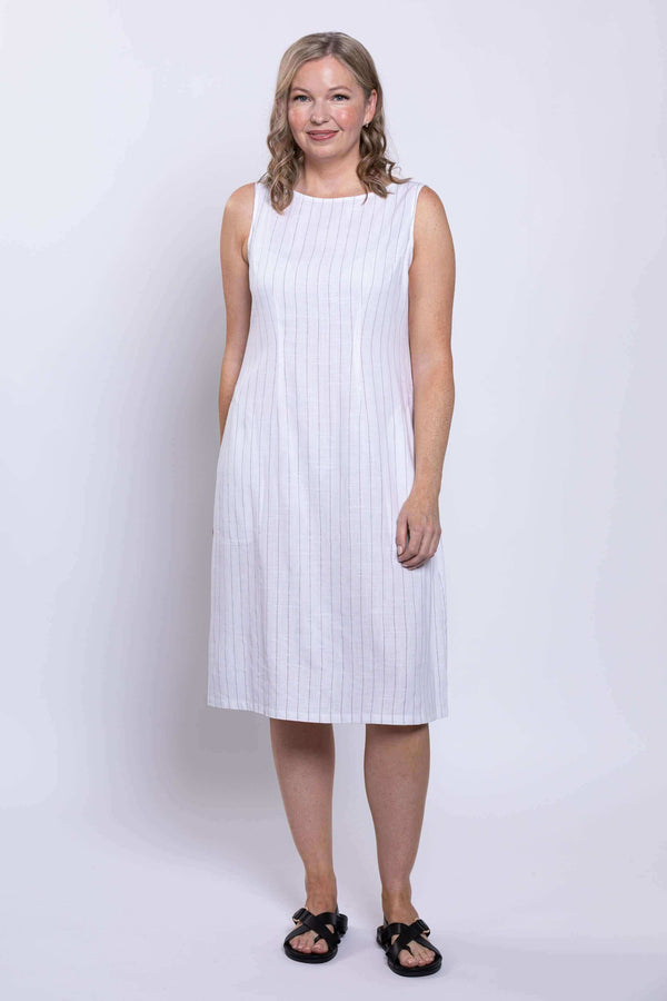 Front view of woman wearing a sleeveless white dress with thin vertical stripes