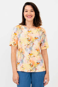 Woman wearing a peach bird print Sky Tee, smiling, front view