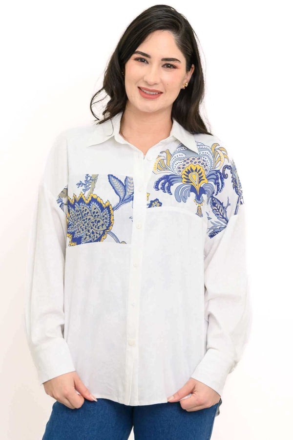 Woman wearing a white blouse with blue and gold floral detail on shoulders, front view