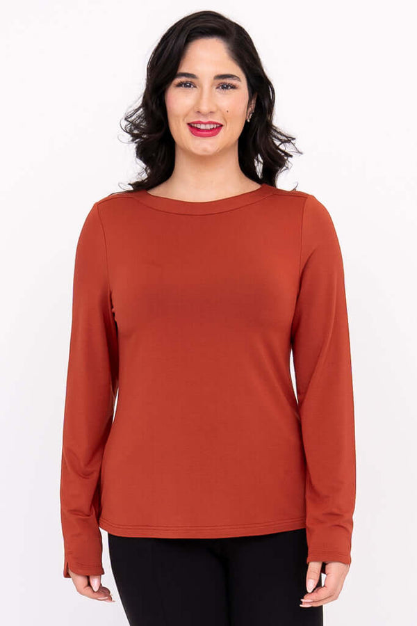 Front view of a woman wearing a rust-colored boat neck long sleeve top