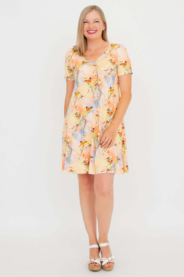 Woman wearing short-sleeved bamboo dress with pastel bird print, front view