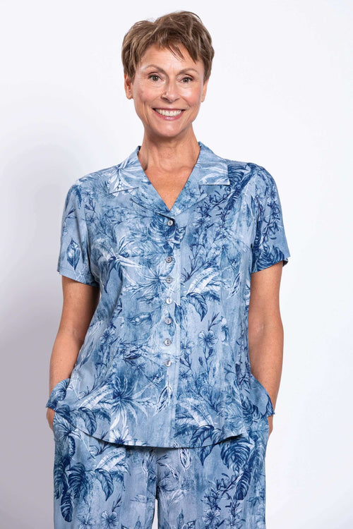 Woman wearing a blue floral short-sleeve button-up shirt with matching pants, front view