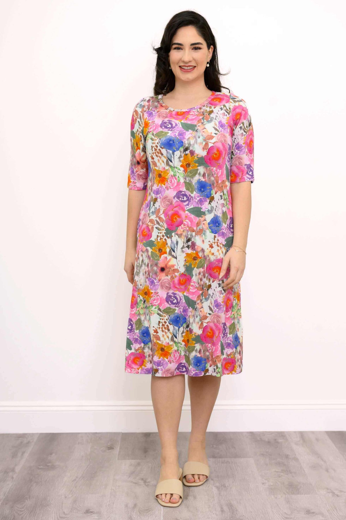 Woman wearing a colorful floral knee-length bamboo dress, front view