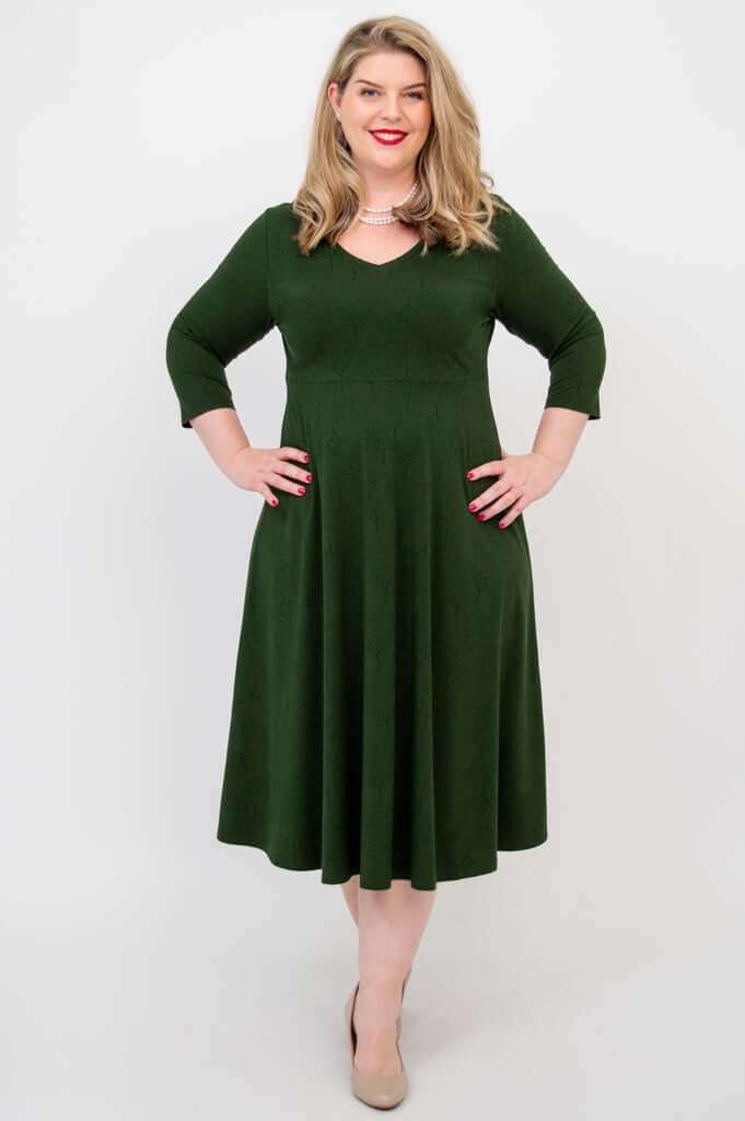 Woman in forest green midi dress posing with hands on hips, front view