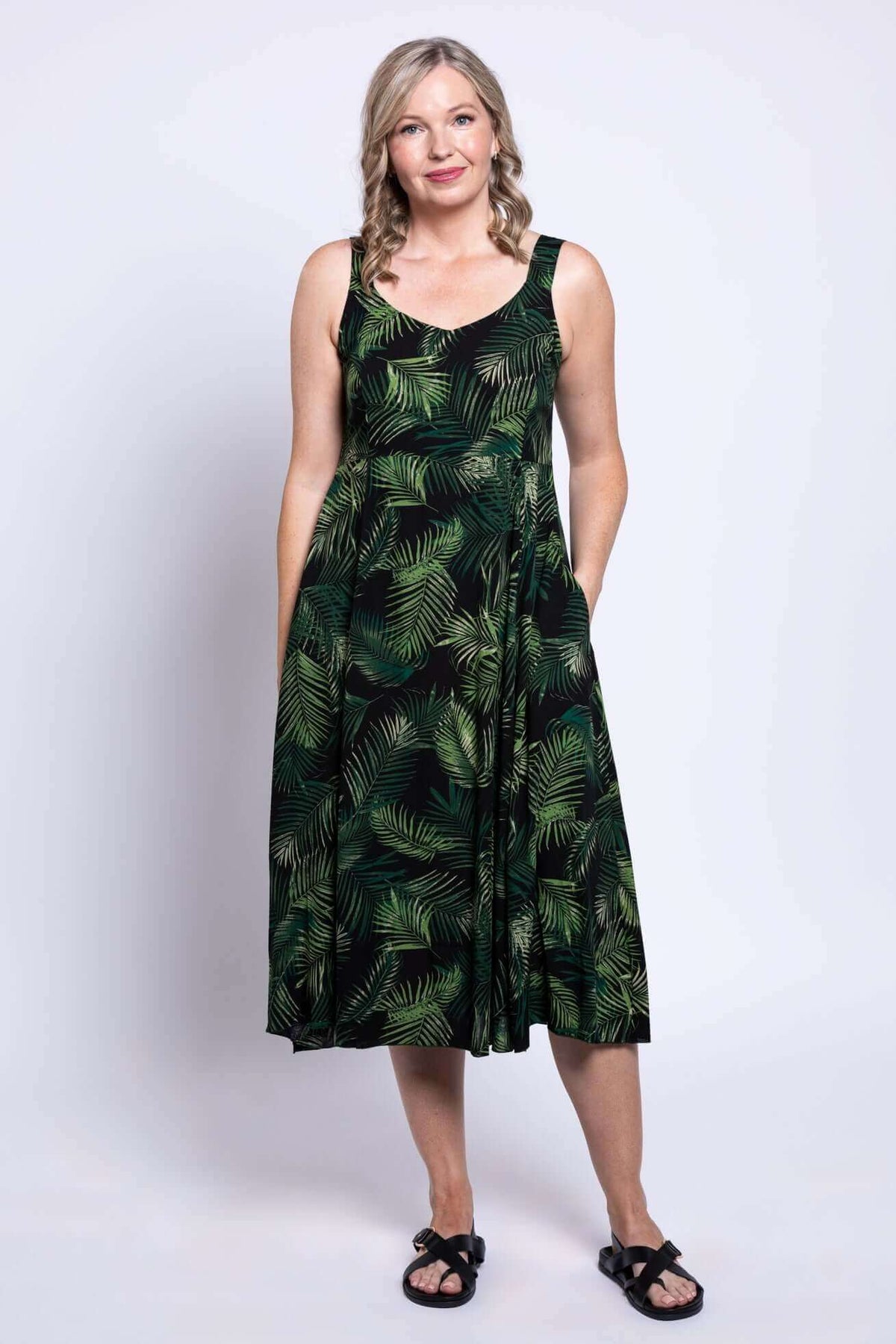 Front view of a woman wearing a green leaf print sleeveless midi dress