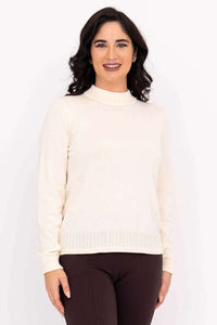 Front view of woman wearing an ivory mock neck sweater and brown pants