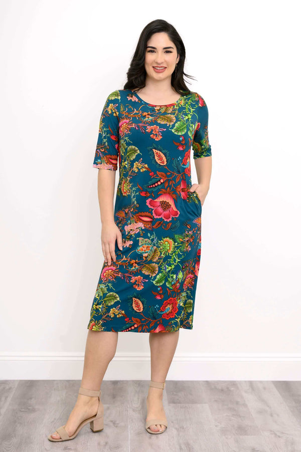 Woman wearing a knee-length floral bamboo dress with short sleeves and pockets, front view
