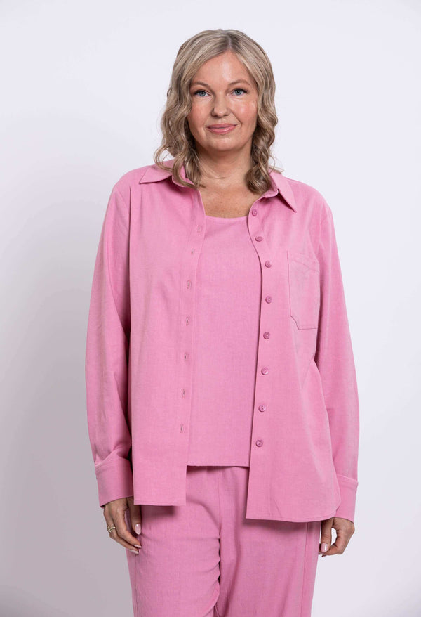 Woman wearing a relaxed fit, long sleeve pink shirt and matching pants, front view upper body