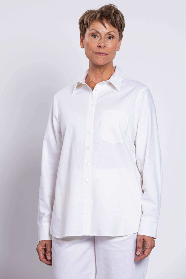 Front view of a woman wearing a relaxed white button-up shirt with breast pocket