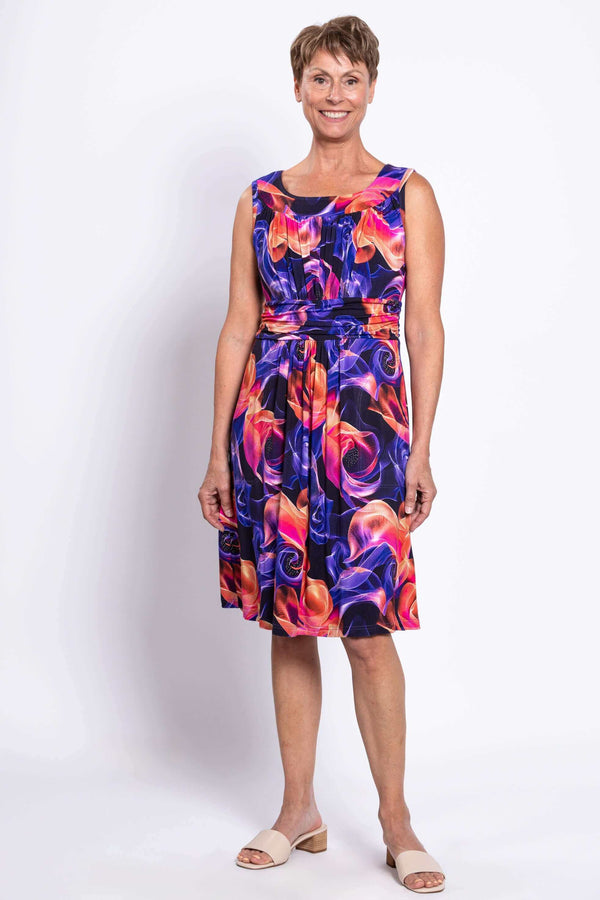 Woman wearing a sleeveless dress with a vibrant swirl print, facing forward