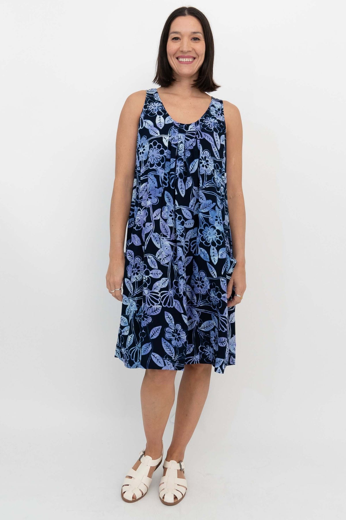Woman wearing a sleeveless navy blue dress with light blue floral print, standing front-facing