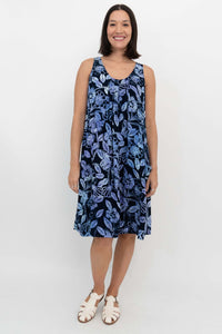 Woman wearing a sleeveless navy blue dress with light blue floral print, standing front-facing