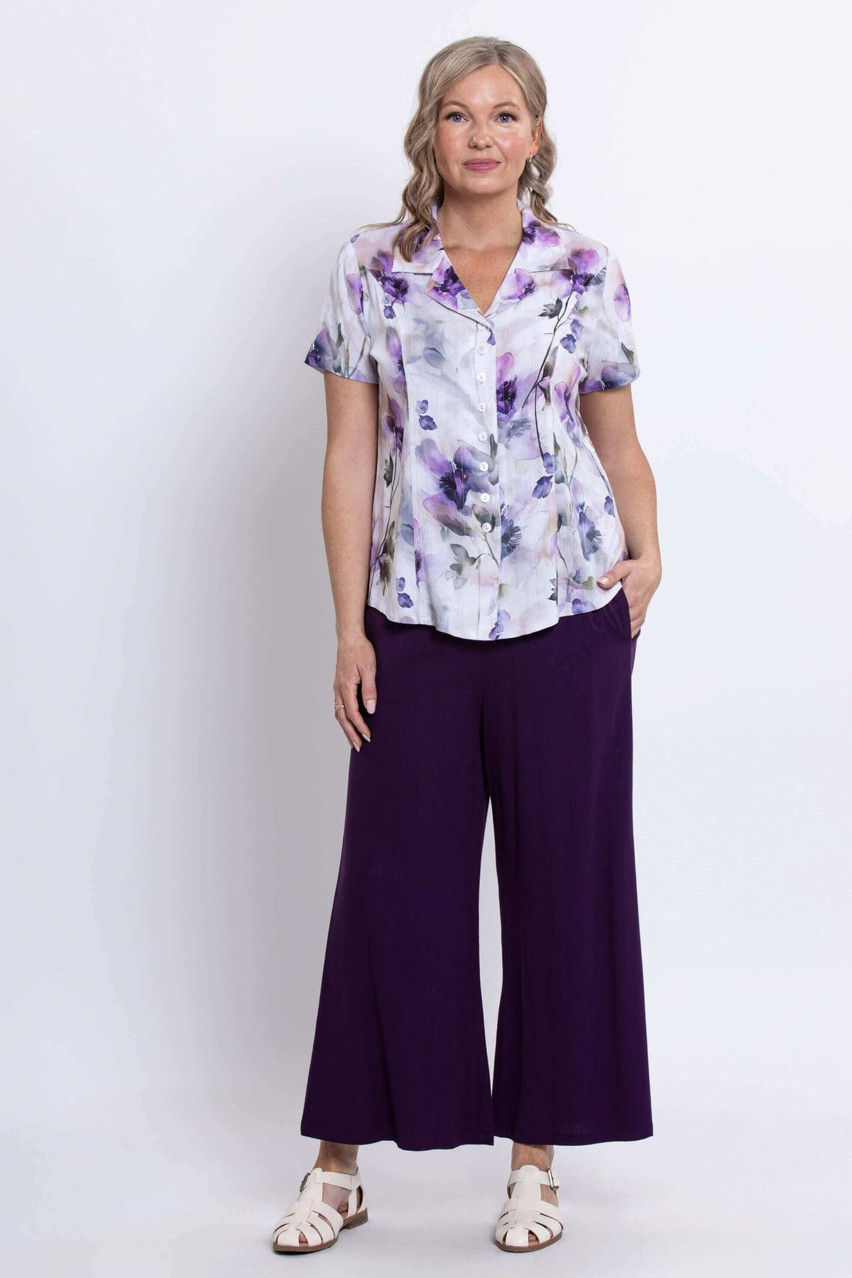 Front view of a woman modeling a floral short sleeve shirt and purple pants