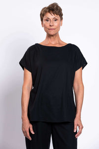 Front view of woman wearing black linen blend tee with boatneck and cap sleeves