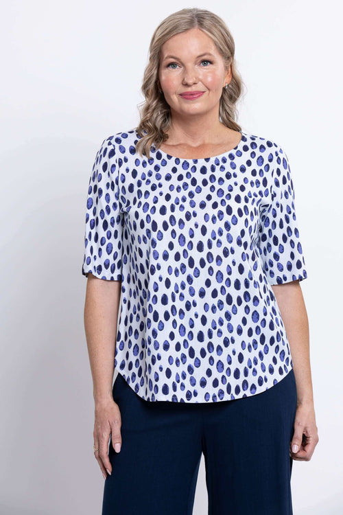 Front view of woman wearing white blouse with navy polka dots and elbow length sleeves