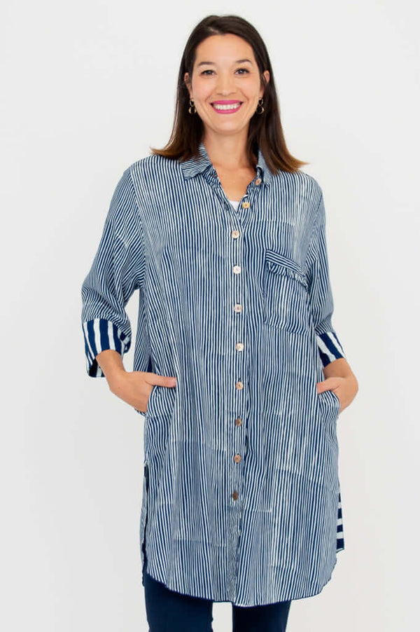 Front view of woman wearing oversized blue striped tunic shirt with contrast cuff and breast pocket