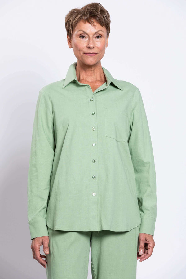 Front view of a woman wearing a sage green button-up shirt and matching pants