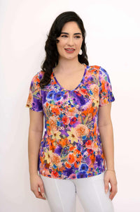 Front view of woman wearing a vibrant floral bamboo top with short sleeves