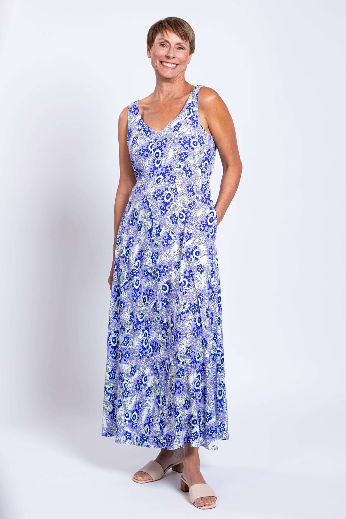 Woman in blue paisley maxi dress, hands in pockets, facing forward