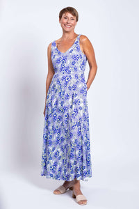 Woman in blue paisley maxi dress, hands in pockets, facing forward