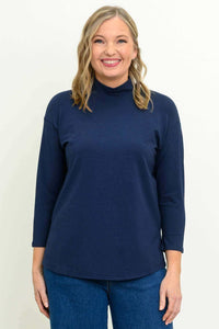 Front view of woman wearing a navy mock neck 3/4 sleeve top and jeans