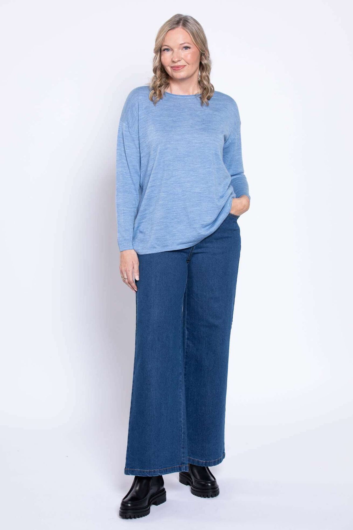 Front view of wide-leg blue denim jeans with light blue top and black boots