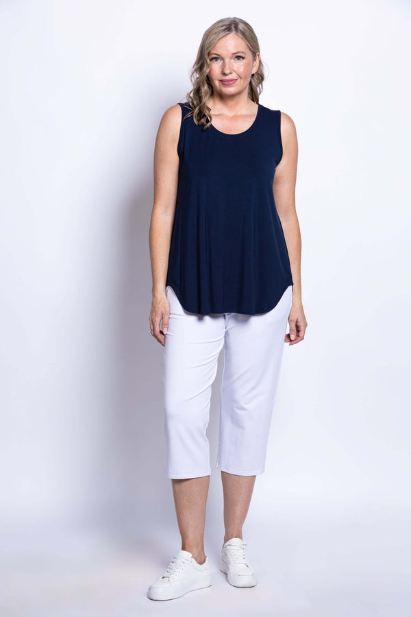 Woman modeling a navy sleeveless tank top and white pants, frontal pose