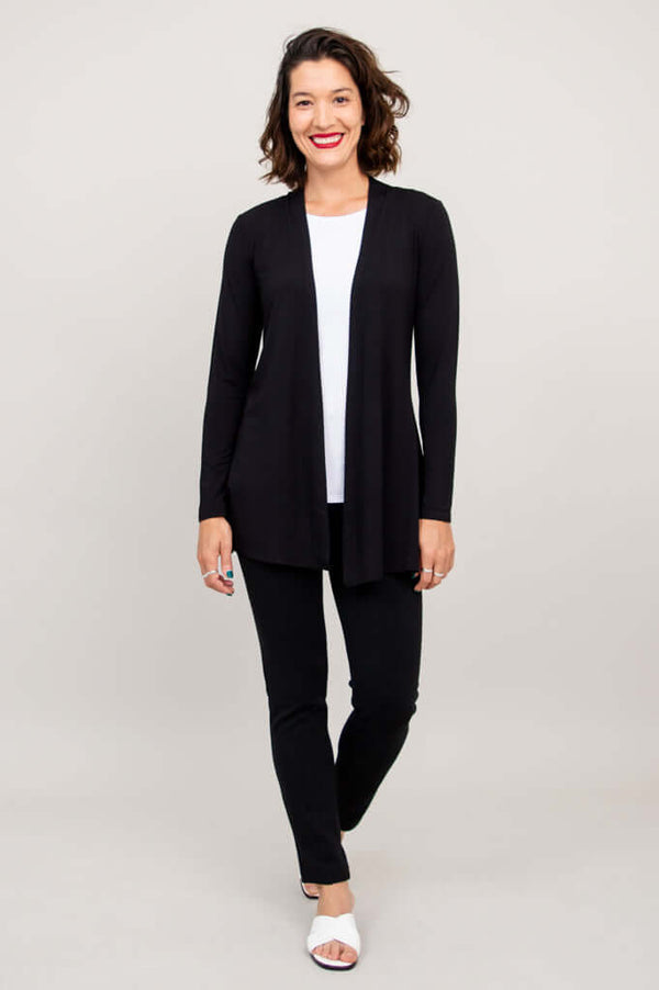Full-body front view of woman modeling the Chopra jacket in black with pants and white sandals