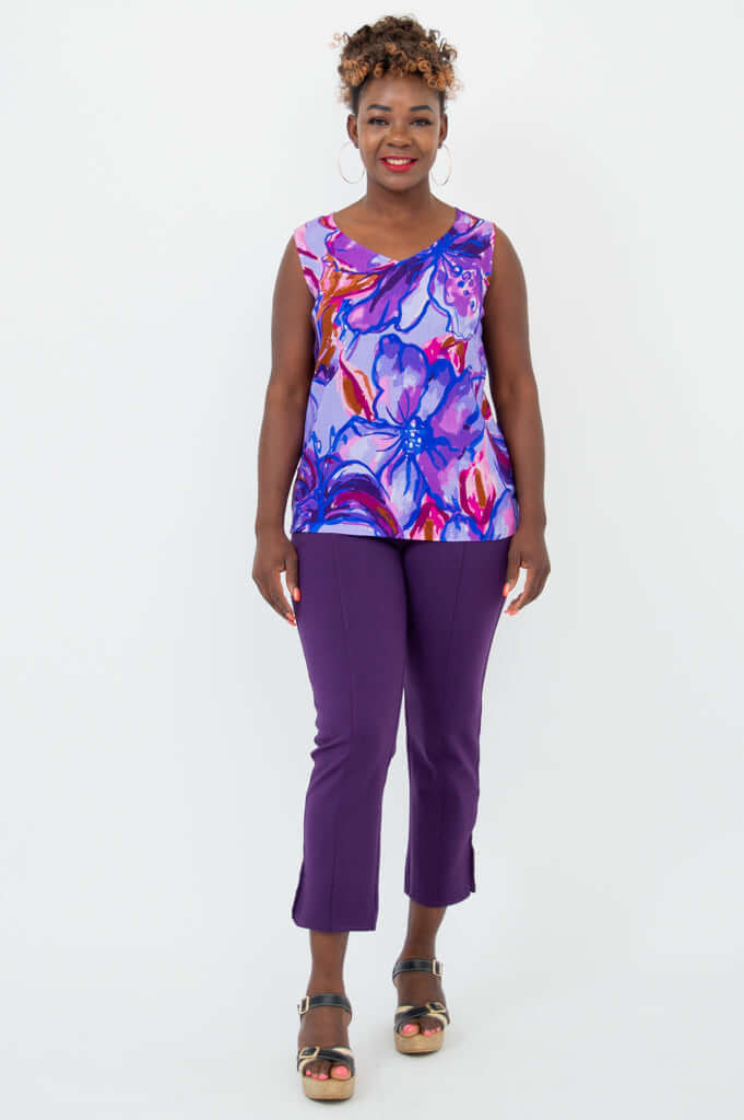 Full-body front view of a woman in a floral V-neck tank and purple pants