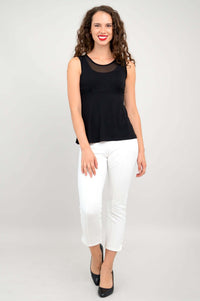 Full-body front view of woman in black mesh tank top and white ankle pants