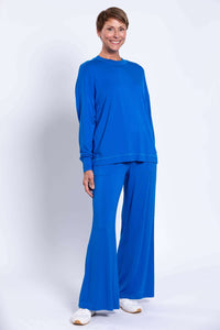 Full-body view of a woman in a matching blue crew neck top and wide-leg pants set