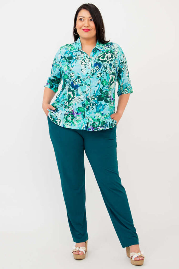 Full-body view of model in a blue and green floral blouse with teal pants
