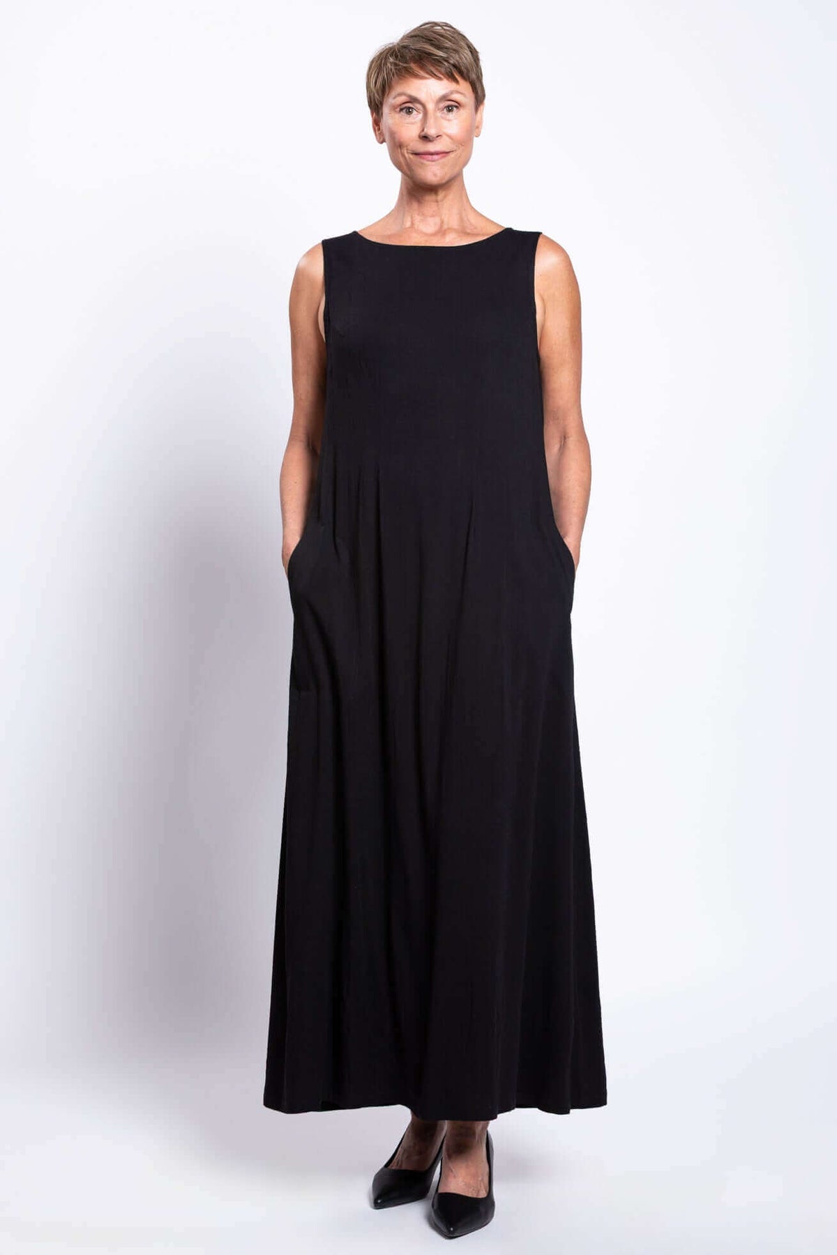Front view of a woman wearing a black shift dress with hands in pockets