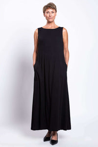 Front view of a woman wearing a black shift dress with hands in pockets