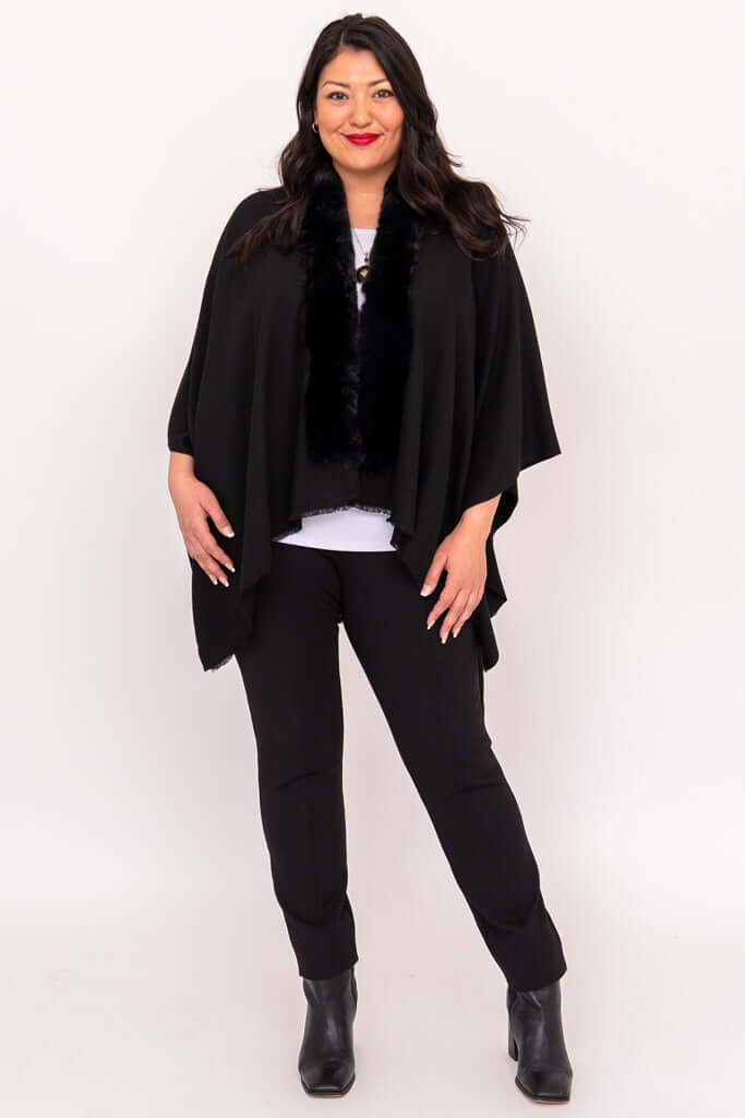 Full-body view of woman in black wrap, white top, black pants, and ankle boots