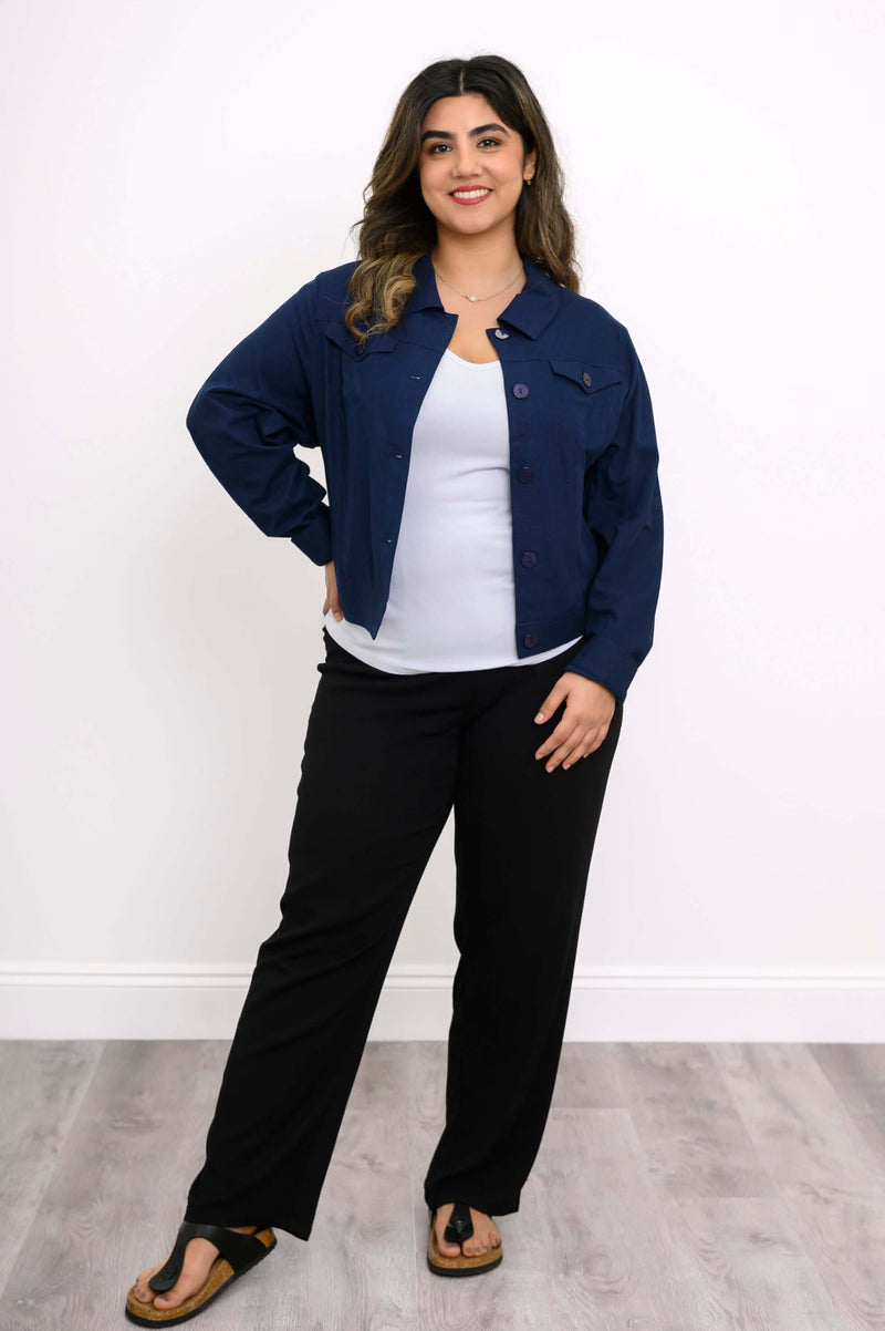 Full-length image of woman modeling a navy blue jean-style jacket with black pants