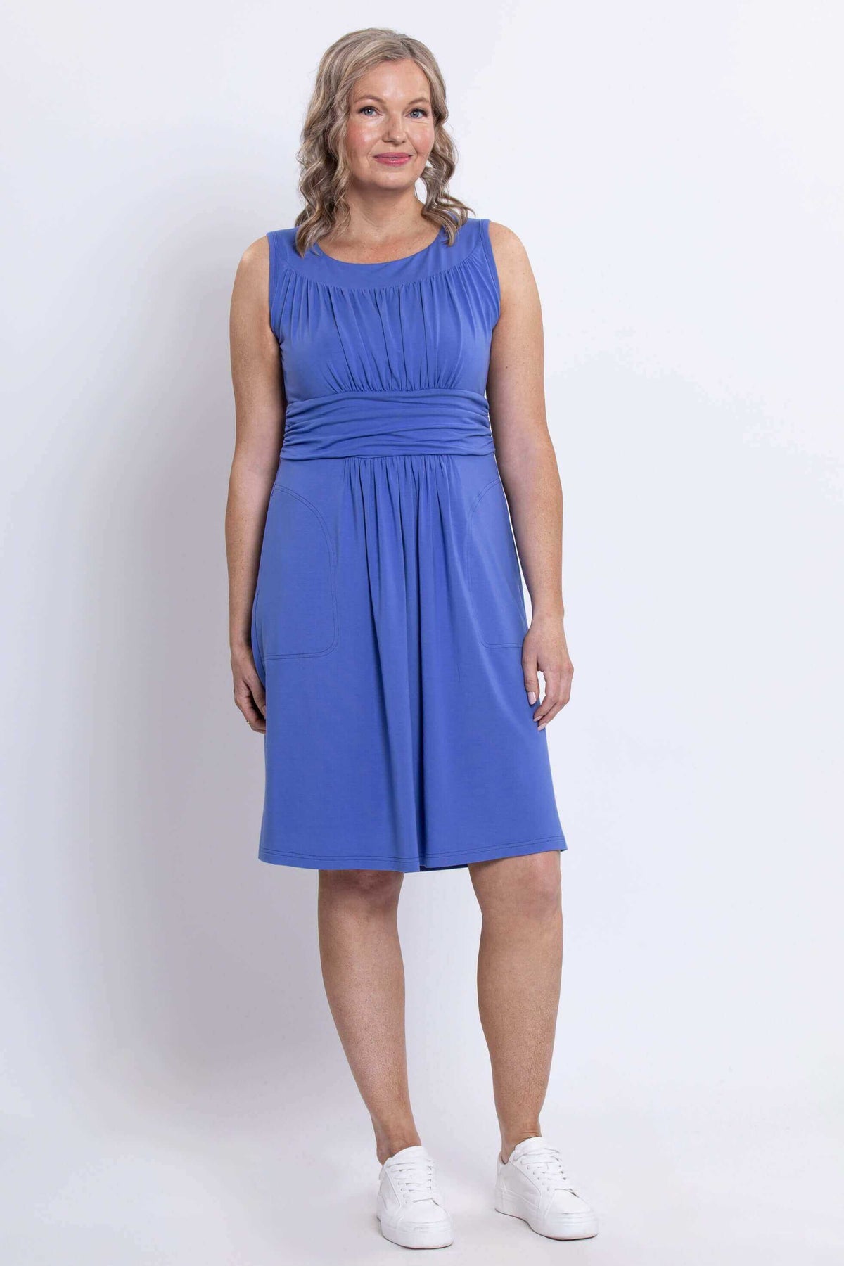 Woman standing in blue dress with fitted waist and pockets, front full-length