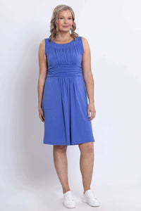 Woman standing in blue dress with fitted waist and pockets, front full-length