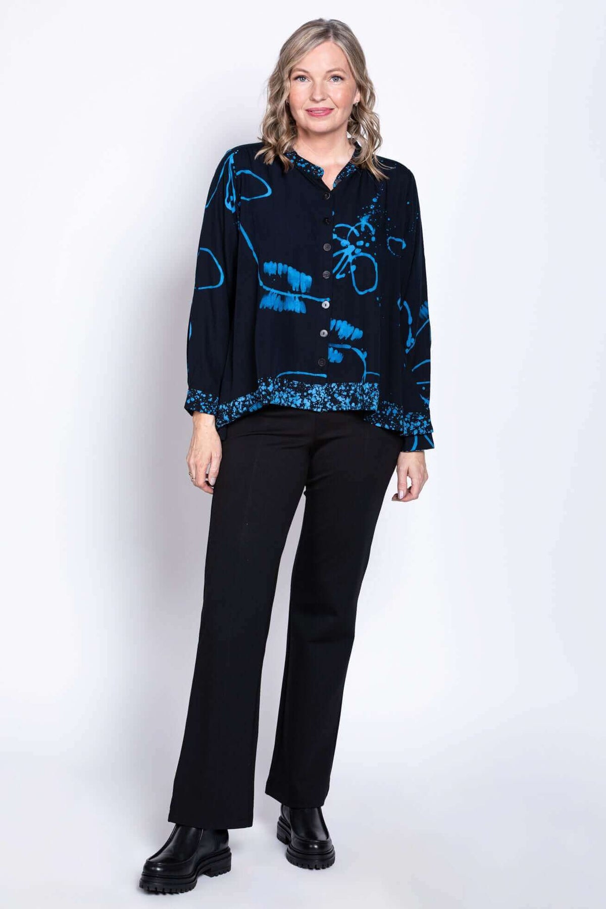 Full body angled front view of woman in black blouse with blue batik design