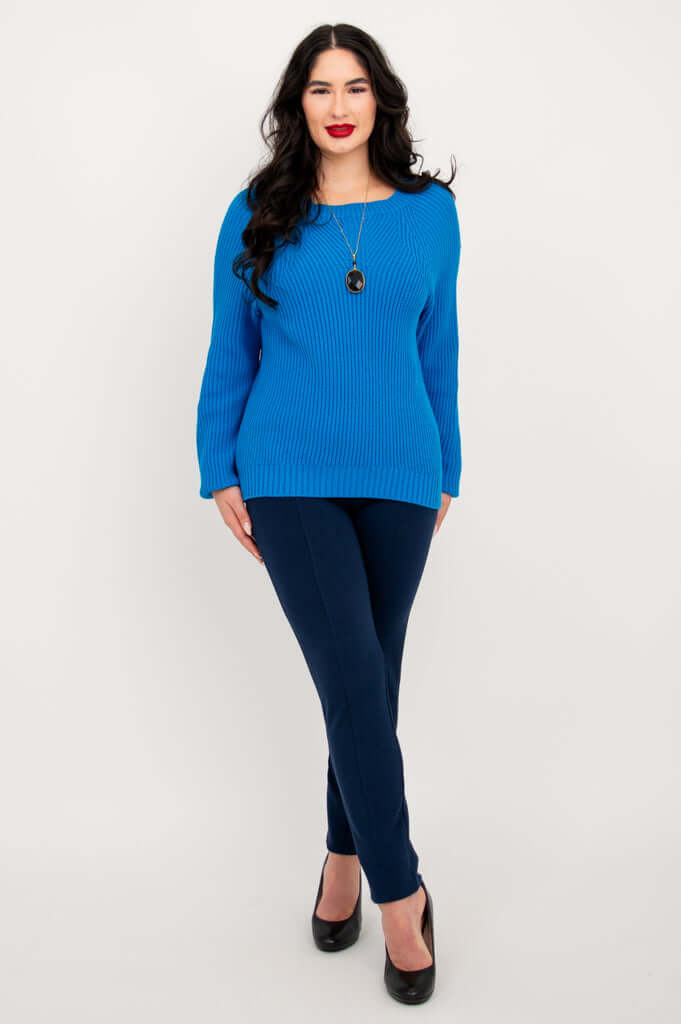 Full body front view of a model in a blue slouchy knit sweater and navy pants