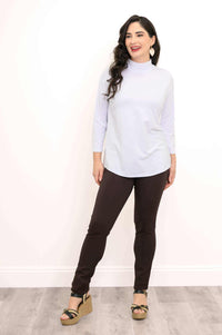 Full body front view of a woman in a white mock neck top and dark pants