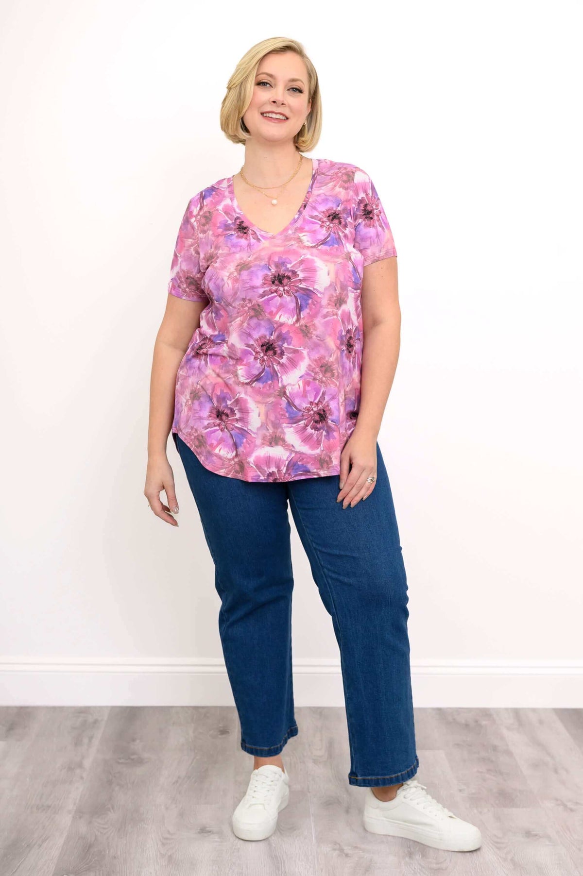 Plus size model in floral v-neck top and jeans, full body front view